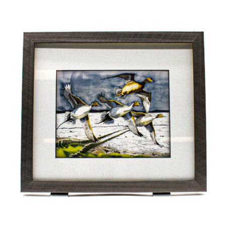 Watercolour-style painting of pintail ducks in flight over a wetland landscape, beneath a dark sky, presented in a dark wooden frame.